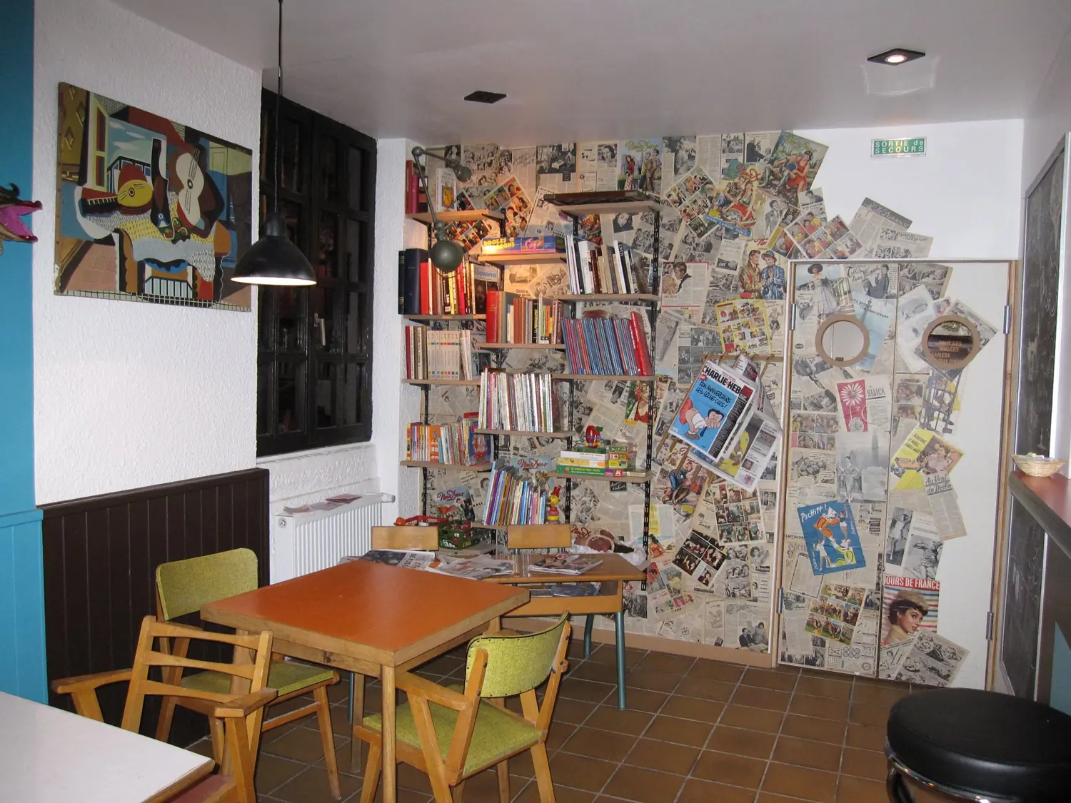 La salle, chaises en formica et mur de journaux